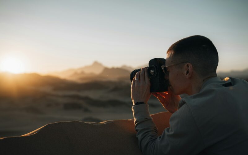 a man taking a picture of the sunset with a camera